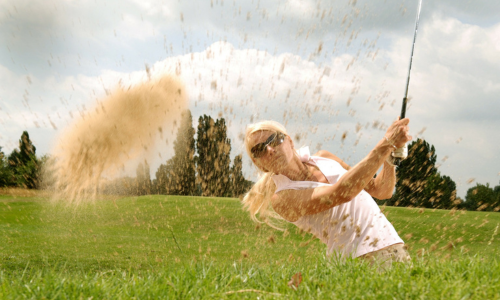 Fairway Fitness: The Health Benefits of Golf for Women, image of a woman playing out of a sand trap on the golf course